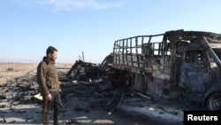 A man views a burnt-out truck near Qamishli International Airport, after regional security sources and officers within the now-fallen Syrian army said that Israeli airstrikes continued against military installations and airbases overnight across Syria, December 10, 2024.