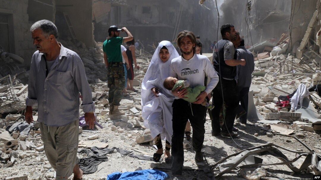 Keluarga Suriah berjalan di antara reruntuhan bangunan yang hancur menyusul serangan udara di distrik Bustan al-Qasr yang dikuasai pemberontak, di utara kota Aleppo (28/4).