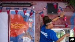 ARCHIVO - Mujer cuelga decoraciones en un camión estacionado cerca del Memorial de la Guerra Civil Afroamericana durante las conmemoraciones del 16 de junio el miércoles 19 de junio de 2024 en Washington.