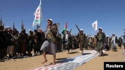 Tribesmen loyal to Houthis march on U.S. and Israeli flags during a military parade for new recruits amid escalating tensions with the U.S.-led coalition in the Red Sea, in Bani Hushaish, Jan. 22, 2024. (Khaled Abdullah/Reuters)