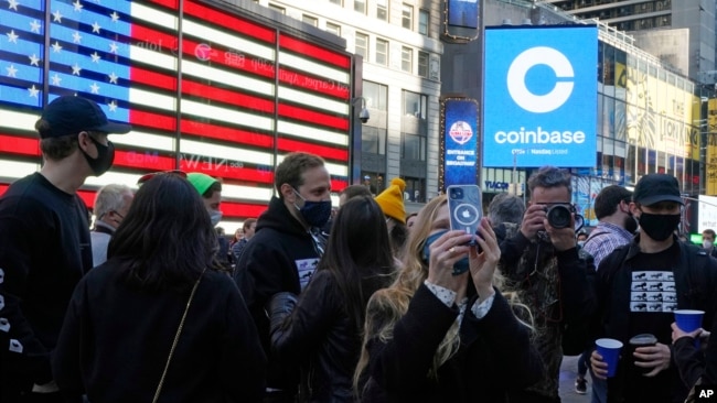 Coinbase employees gather outside the Nasdaq MarketSite during the company's IPO, in New York's Times Square, Wednesday, April 14, 2021. 