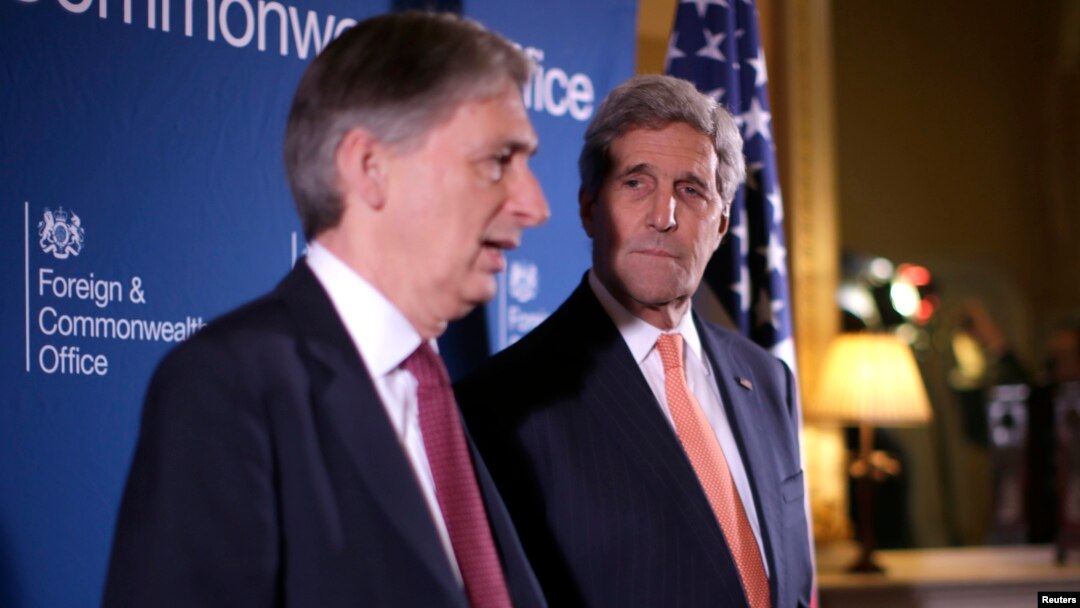 Menlu AS John Kerry (kanan) mendengarkan penjelasan Menlu Inggris Philip Hammond dalam pertemuan dengan anggota koalisi membahas isu terkait ISIS di Lancaster House, London (22/1).