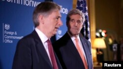 Menlu AS John Kerry (kanan) mendengarkan penjelasan Menlu Inggris Philip Hammond dalam pertemuan dengan anggota koalisi membahas isu terkait ISIS di Lancaster House, London (22/1).