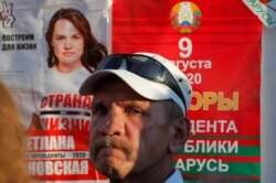A man stands next to an election campaign poster during a rally held by supporters of Svetlana Tikhanouskaya, a candidate in the upcoming presidential election and President Alexander Lukashenko's main challenger, in Minsk, Belarus, Aug. 6, 2020.