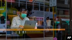 A man wearing a face mask sits at a coffee shop in Hong Kong, Feb. 22, 2020. COVID-19 viral illness has sickened tens of thousands of people in China since December.
