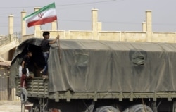 FILE - A Syrian boy holds the Iranian flag as a truck carrying aid provided by Iran arrives in the eastern city of Deir el-Zour, Sep. 20, 2017.