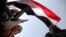 A boy holding a weapon stands under a Yemeni national flag, as followers of the Houthi group demonstrate against an arms embargo imposed by the U.N. Security Council on the group in Sanaa, April 16, 2015.