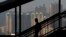 FILE - A woman walks down a stairway against the backdrop of high-rise apartment buildings in Hong Kong.