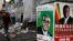 Election campaign posters are pictured near Zimbabweans walking on a street blocked by uncollected garbage in Harare July 17, 2013.