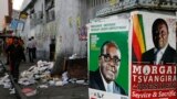 Election campaign posters are pictured near Zimbabweans walking on a street blocked by uncollected garbage in Harare July 17, 2013. President Robert Mugabe&#39;s rivals said the chaotic organisation of early voting for soldiers and police showed Zimbabwe was not ready for the July 31 general election in which nearly six million people had registered to vote.