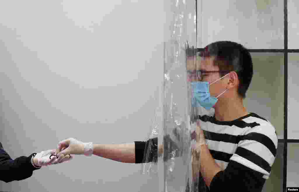 An employee of a store wears a face mask and work behind a plastic curtain as a precaution against the spread of the coronavirus disease (COVID-19) in Vina del Mar, Chile, March 14, 2020.