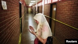 Seorang perempuan Muslim Bosnia berdoa di koridor ruangan-ruangan tempat tahanan disiksa pada peringatan 20 tahun penutupan kamp penahanan Omarska di Bosnia dan Herzegovina awal Agustus. (Foto: Reuters)