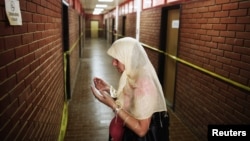 A Bosnian Muslim woman prays along a corridor with rooms where inmates were tortured, during the 20th anniversary of the closure of the Omarska detention camp in Omarska, Bosnia and Herzegovina, August 6, 2012.