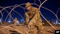 Un soldado de la Guardia Nacional de Texas amarra hileras de alambre de púas para instalarlo cerca de una entrada en la valla fronteriza, el jueves 11 de mayo de 2023, en El Paso, Texas, EEUU.