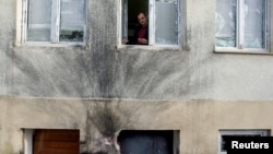 FILE - Editor-in-chief of Montenegro's leading daily Vijesti, Mihailo Jovovic looking through a window damaged in a bomb blast at the newspaper's offices in Podgorica, Dec. 27, 2013