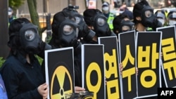 South Korean environmental activists wearing gas masks hold placards during a protest against Japan's decision to discharge Fukushima wastewater into the sea, near the Japanese Embassy in Seoul, June 4, 2021, a day before World Environment Day.