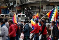 Police patrol on the sidelines of a march by supporters of former President Evo Morales, arriving from El Alto and entering La Paz, Bolivia, Nov. 12, 2019.