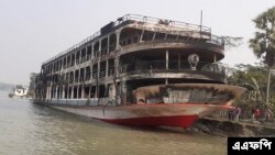 ঢাকা থেকে ২৫০ কিলোমিটার (১৬০ মাইল) দক্ষিণে ঝালকাঠিতে আগুনে পুড়ে যাওয়ার একদিন পর উপকূলে নোঙর করা হয়েছে ফেরিটি। ২৪ ডিসেম্বর ২০২১।(ছবি আরিফুর রহমান / এএফপি)