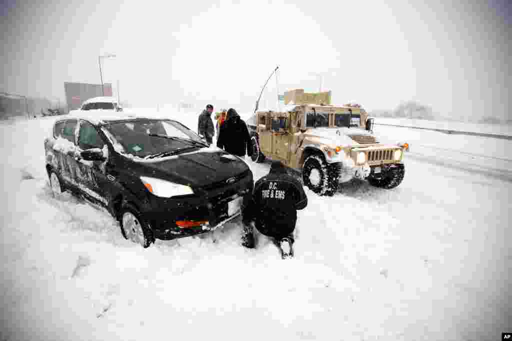 Soldiers with the 275th Military Police company, and a Washington Firefighter, in a Humvee, assist a stranded motorist in the snow on I-395, Saturday, Jan. 23, 2016 in Washington. (AP Photo/Alex Brandon)