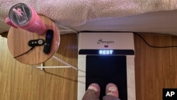 FILE - Hope Zuckerbrow, founder of the cozy cardio wellness movement, shows her workout set-up, including a walking pad, smoothie and remote control for watching television. (Hope Zuckerbrow via AP)