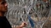 A migrant touches a razor wire fence at the border with Hungary near the village of Horgos, Serbia, September 16, 2015. (Stoyan Nenov/Reuters)