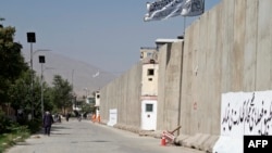 On Sept. 3, 2024, Afghan men walk near the site where the day before a suicide bomber triggered explosives in Kabul. The blast killed at least six people and wounded 13, authorities say.