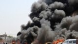An Iraqi policeman stands near burning vehicles moments after one in a series of bombs hit the Shiite stronghold of Sadr City, in Baghdad, Iraq, killing tens.