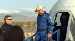 This photo provided by Blue Origin, Jeff Bezos, founder of Amazon and space tourism company Blue Origin, exits the Blue Origin's New Shepard capsule after it parachuted safely down near Van Horn, Texas, July 20, 2021.