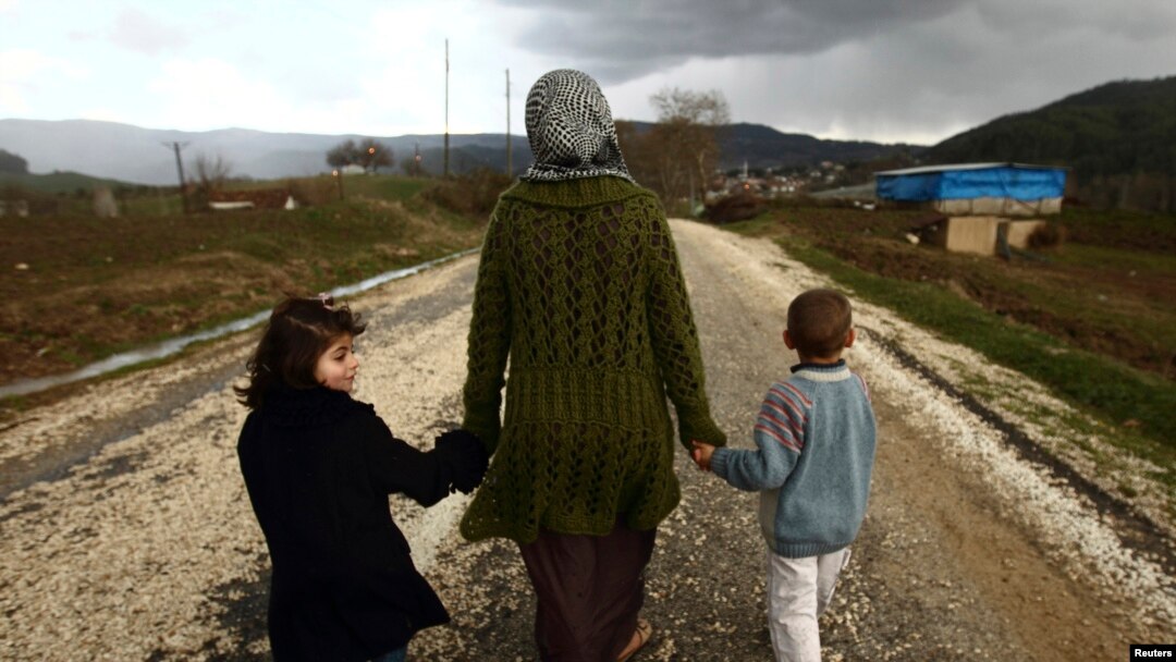 Siriyalik ayol farzandlari bilan Turkiya chegarasi yaqinidagi qochqinlar lagerida boshpana topgan. 