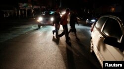 FILE - People walk on a street during a blackout in Caracas, Venezuela, Dec. 2, 2013.