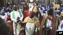 Anglican Bishop Nolbert Kunonga, front center, in church as members of Anglican church supporting him hold placards attacking homosexuality and condemning the visit by Britain's Archbishop of Canterbury Rowan Williams, in Harare, Oct. 9, 2011.