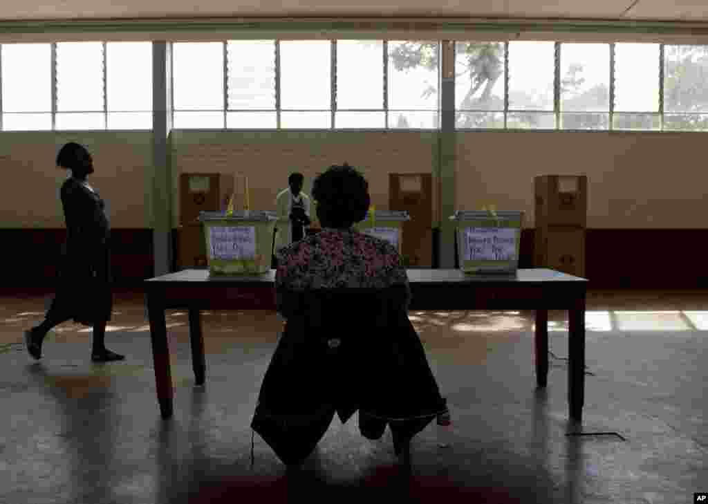 An electoral worker watches as voters cast ballots in a Harare suburb, July 31, 2013.