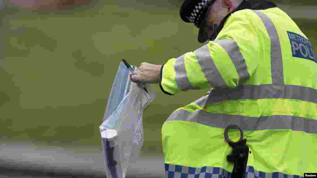 A police officer carries an evidence bag containing a knife near the scene of the killing of a British soldier in Woolwich, London, May 23, 2013. 