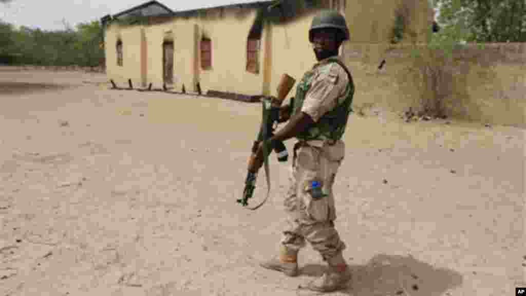 A soldier stands guard outside of a church that Islamic extremists burned in an earlier attack in Marte, Nigeria.