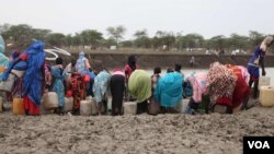 Women who recently crossed over from Sudan's Blue Nile state with little food or water fill jerry cans at a watering hole called km 18, June 20, 2012 (H. McNeish/VOA)