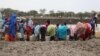 Women who recently crossed over from Sudan's Blue Nile state with little food or water fill jerry cans at a watering hole called km 18, June 20, 2012 (Hannah McNeish/VOA)