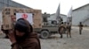 FILE - An Afghan man carries an aid package he received at a distribution site in Kabul, Afghanistan, Dec. 15, 2021, as Taliban fighters stand in the background.