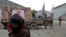 FILE - An Afghan man carries an aid package he received at a distribution site in Kabul, Afghanistan, Dec. 15, 2021, as Taliban fighters stand in the background.