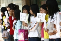 A group of unemployed Chinese graduates hold signs offering themselves as tutors, along a street in Shenyang, northeast China's Liaoning province on May 26, 2007.