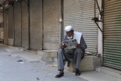 A man reads a morning newspaper at a market closed due to new restrictions to control the spread of the coronavirus, in Peshawar, Pakistan, May 1, 2021.