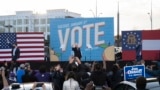 Democratic candidates for Senate Jon Ossoff (L), Raphael Warnock (R) and US President-elect Joe Biden (C) wave from stage during a rally outside Center Parc Stadium in Atlanta, Georgia, on January 4, 2021. - President Donald Trump, still seeking ways to r