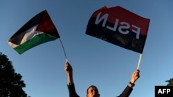 Seorang pria mengacungkan bendera Palestina dan Sandinista saat peresmian jalan Gaza untuk mendukung rakyat Palestina, di pusat Kota Managua yang bersejarah, di Nikaragua, 30 Januari 2024. (Foto: Oswaldo Rivas/AFP)