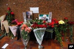 Flowers and tributes are placed outside the Iranian Embassy in Kyiv, Ukraine, Jan. 10, 2020, with a poster that reads: "Tehran - Kyiv, we're mourning" for the victims of the Ukrainian plane that crashed on the outskirts of Tehran, Iran.