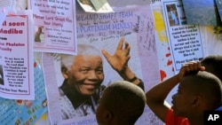 Young boys read get well messages with a photograph of former South African President Nelson Mandela, outside the Mediclinic Heart Hospital where he is being treated in Pretoria, South Africa, July 1, 2013.