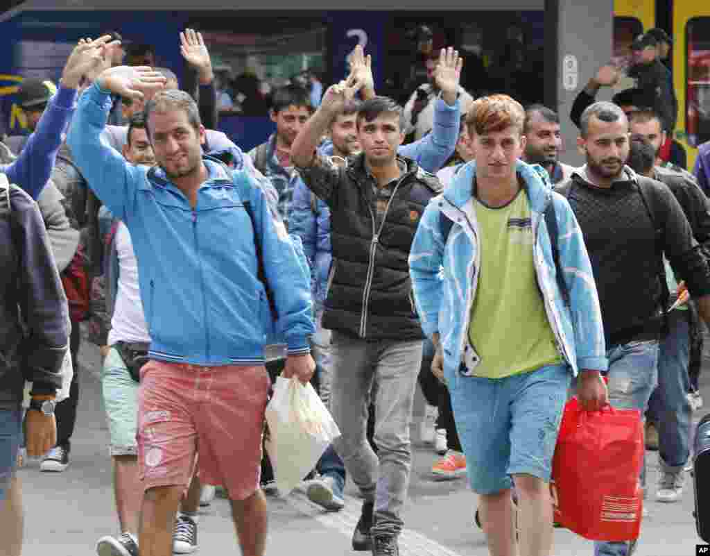 Refugees wave as they arrive at the main train station in Munich, Germany, Saturday, Sept. 5, 2015. Hundreds of refugees arrived in various trains to get first registration as asylum seekers in Germany. 