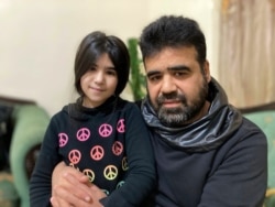 Syrian refugee Mahmoud Mansour, 47, sits with daughter Sahar, 8, at his rented apartment in Amman, Jordan, Jan. 20, 2021. U.S. President Joe Biden said April 17, 2021, that his administration would boost the number of refugees admitted to the U.S.