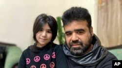 FILE - Syrian refugee Mahmoud Mansour, 47, sits with daughter Sahar, 8, at his rented apartment in Amman, Jordan, Jan. 20, 2021. U.S. President Joe Biden said April 17, 2021, that his administration would boost the number of refugees admitted to the U.S.