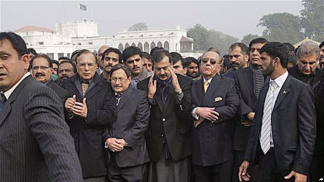 Pakistani Prime Minister Yousuf Raza Gilani, center, surrounded by officials and members of his government, offers a prayer during the funeral procession of Punjab Gov. Salman Taseer in Lahore, Pakistan, Jan 5, 2011