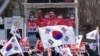 A TV screen shows a file image of South Korean President Yoon Suk Yeol as supporters of impeached Yoon stage a rally to oppose his impeachment near the presidential residence in Seoul, Jan. 7, 2025.