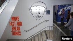 People walk past graphic on a wall at Facebook headquarters, Menlo Park, California, Jan. 29, 2013.